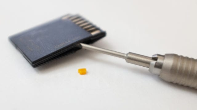 Image of SD Card with the switch removed and a screwdriver used to split the card.