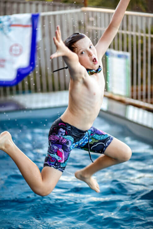 family photo boy jumping into pool