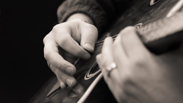 Close up of hands playing a guitar after Luminar AI Sepia Toning