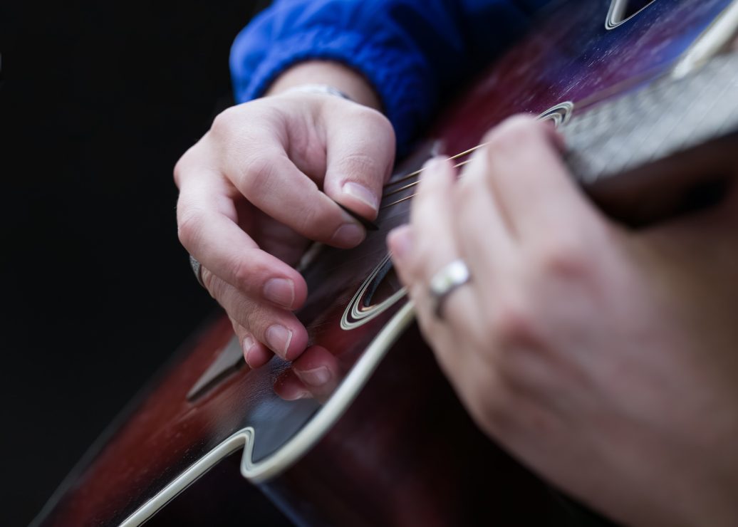 Close up of hands playing a guitar before Luminar AI Sepia Toning